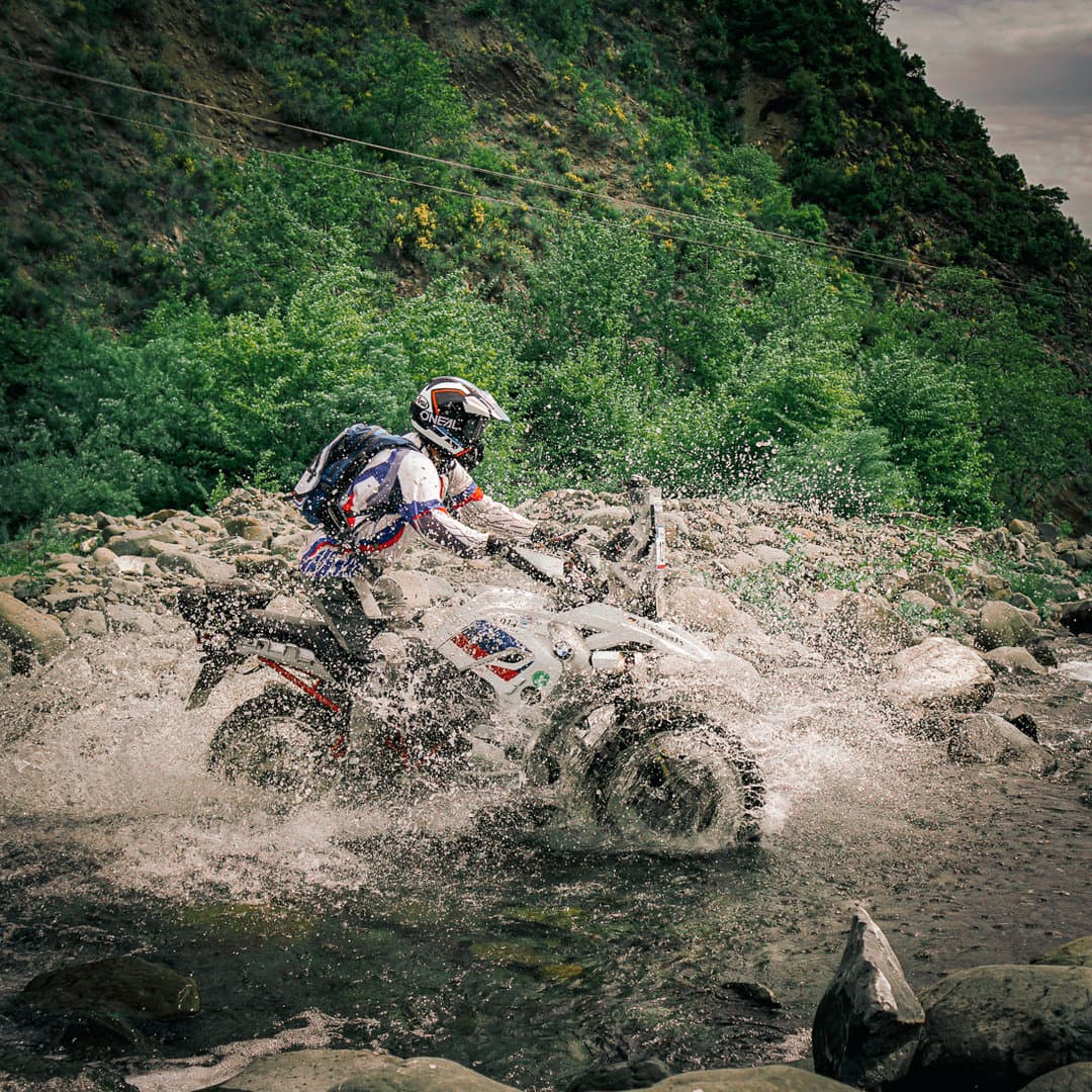 Reiseenduro durchquert einen steinigen Bach